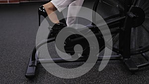 Close-up of a business woman in high-heeled shoes pedaling on an exercise bike.