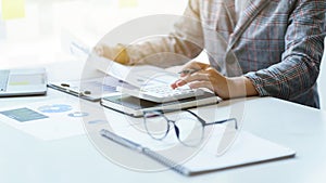 Close up a Business woman holding pen pointing to business chart paper for doing math finance on a wooden desk, tax, accounting,