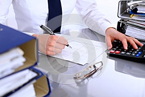 Close up of business woman making report, calculating or checking balance.