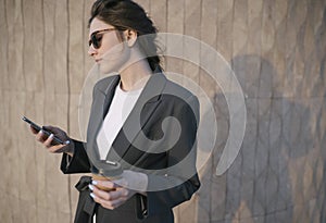 Close-up business woman`s hands hold lactose-free coffee and phone. Business woman at lunch solves work issues using the