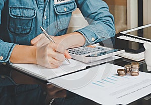 Close up of business woman`s hands writing on a paper on the table and working calculating monthly home expenses, taxes.