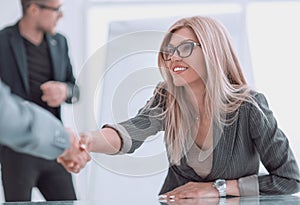Close up. business woman shaking hands sitting behind a Desk.