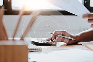 Close up Business woman using calculator and laptop for do math finance on wooden desk