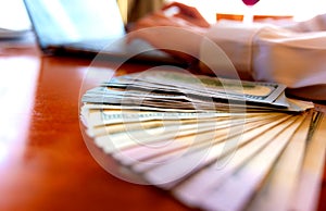 Close-up A business woman working in a private room, She is typing on laptop keyboard, stack of dollar bills in the