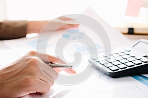 Close up of businessman or accountant hand holding pen working on calculator to calculate business data,