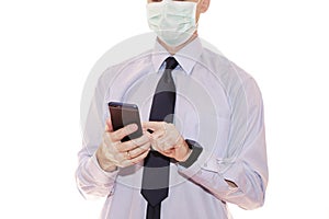 Close-up - businessman in a blue shirt and protective medical mask holds a smartphone in his hand