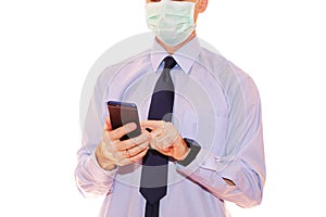 Close-up - businessman in a blue shirt and protective medical mask holds a smartphone in his hand