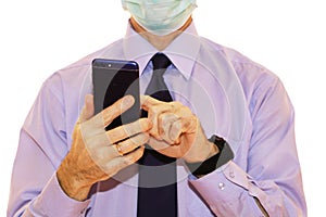 Close-up - businessman in a blue shirt and protective medical mask holds a smartphone in his hand