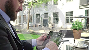 Close up, businessman browsing tablet. Outdoor. Steadicam shot.