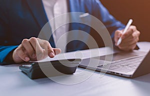 Close-up businessman calculates financials with smartphone and laptop on the desk. Concept for finance, business, banking, and