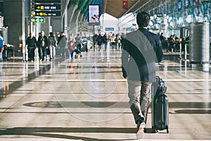 Close up of businessman carrying suitcase while walking through a passenger departure terminal in airport. Businessman traveler