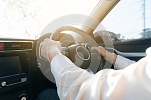 Close up businessman is driving car, hands holding steering wheel