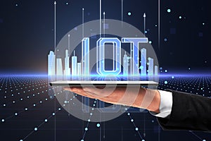 Close up of businessman hand holding cellphone with creative glowing digital mesh city and iot hologram on blurry background.