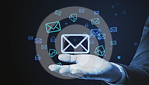 Close up of businessman hand holding glowing email letter icons on dark blue background. Communication and business message