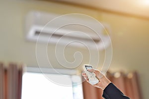 Close up of businessman hand holding remote control directed adjusting of air conditioner