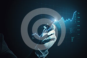 Close up of businessman hand with pen pointing at glowing digital business chart grid. Success, money, metaverse and statistics