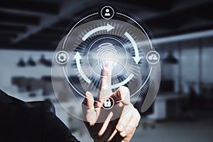Close up of businessman hand pointing at abstract glowing fingerprint id scanning interface on blurry office background.
