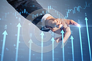 Close up of businessman hand pointing at growing blue vertical arrows and candlestick forex chart on blurry index grid background