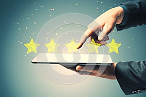 Close up of businessman hand pointing at tablet with 5 star rating on blurry background. Customer service and excellent feedback