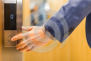 Close up of businessman hand pressing modern elevator button