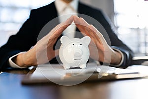 Close-up Of Businessman Hand Protecting Piggy