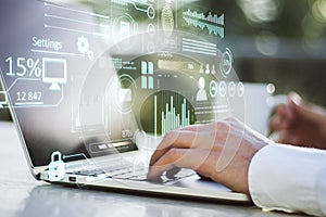 Close up of businessman hand using laptop keyboard on desktop with coffee cup and creative glowing business chart interface