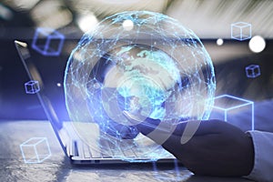 Close up of businessman hand using laptop keyboard and smartphone with reative glowing blue globe metaverse on blurry background.