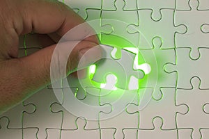 Close up of businessman hands connecting puzzle element and making jigsaw complete. Puzzle jigsaw with green light.