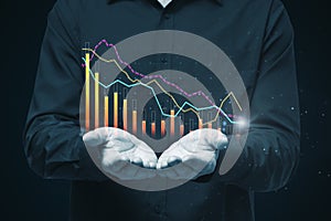 Close up of businessman hands holding creative glowing business graph on black background. Toned image. Finance, annual report and
