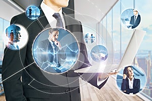 Close up of businessman hands holding laptop with abstract glowing communication and connections holograms with people on blurry