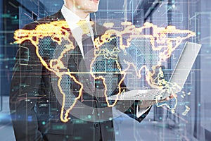 Close up of businessman hands holding laptop with abstract glowing golden map hologram on blurry office interior background.