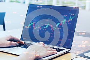 Close up of businessman hands using laptop computer with abstract candlestick forex graph and bid data numbers on blurry desktop