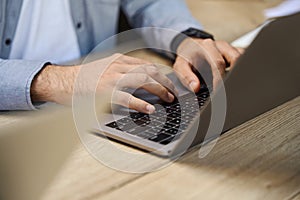 Close up of businessman hands using laptop computer at wooden desk