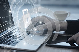 Close up of businessman hands using laptop keyboard on desktop with glowing circuit padlock hologram on blurry background. Secure