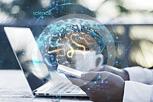Close up of businessman hands using laptop and smartphone with creative brain hologram on blurry background. Science, future,