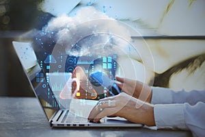 Close up of businessman hands using laptop and smartphone on desktop with coffee cup and abstract hologram raining cloud on blurry