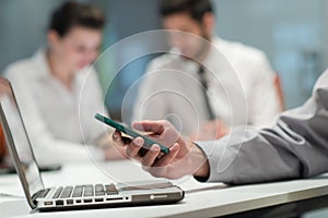 Close up of businessman hands using smart phone on meeting