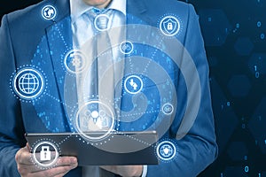 Close up of businessman hands using tablet with connected digital business interface with various icons and binary code on blurry