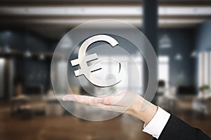 Close up of businessman holding abstract euro sign on blurry office interior background. Finance and income concept