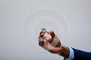 Close up of businessman holding bulb screw base against grey background