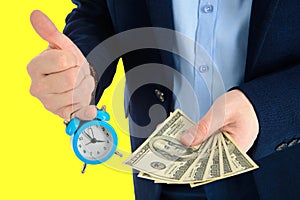 Close up of businessman holding a clock and one stack of cash in hand, time and money concept. Thumbs up.