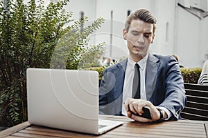 Close up of businessman holding mobile phone in hand and looking at watches.