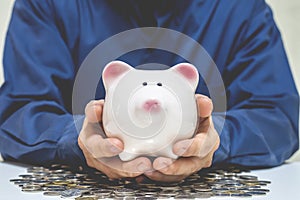 Close up of businessman holding piggy bank and money coin , saving money for future investment concept