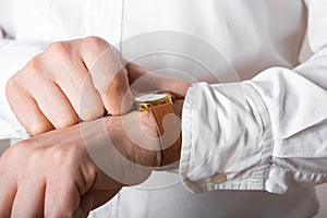 Close up of businessman looking at watch on his hand free space. Man in white shirt checking time from luxury wristwatches. Groom