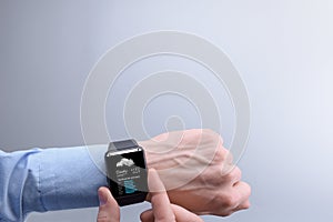 Close-up of a businessman man male checking weather on smartwatch app program on a background of blue sky with white clouds