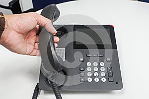 Close up businessman off hook IP phone calling out