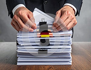 Businessman Managing Large Document Files with Clips and Paperwork