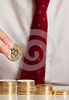 Close up businessman putting bitcoins on a pile