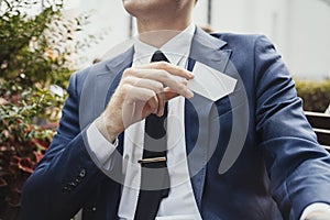 Close up of businessman putting blank business card in his blue jacket pocket.