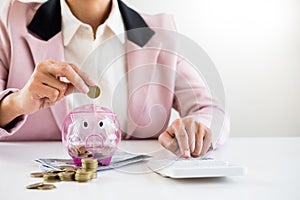 Close up of Businessman putting coin into small piggy bank , The